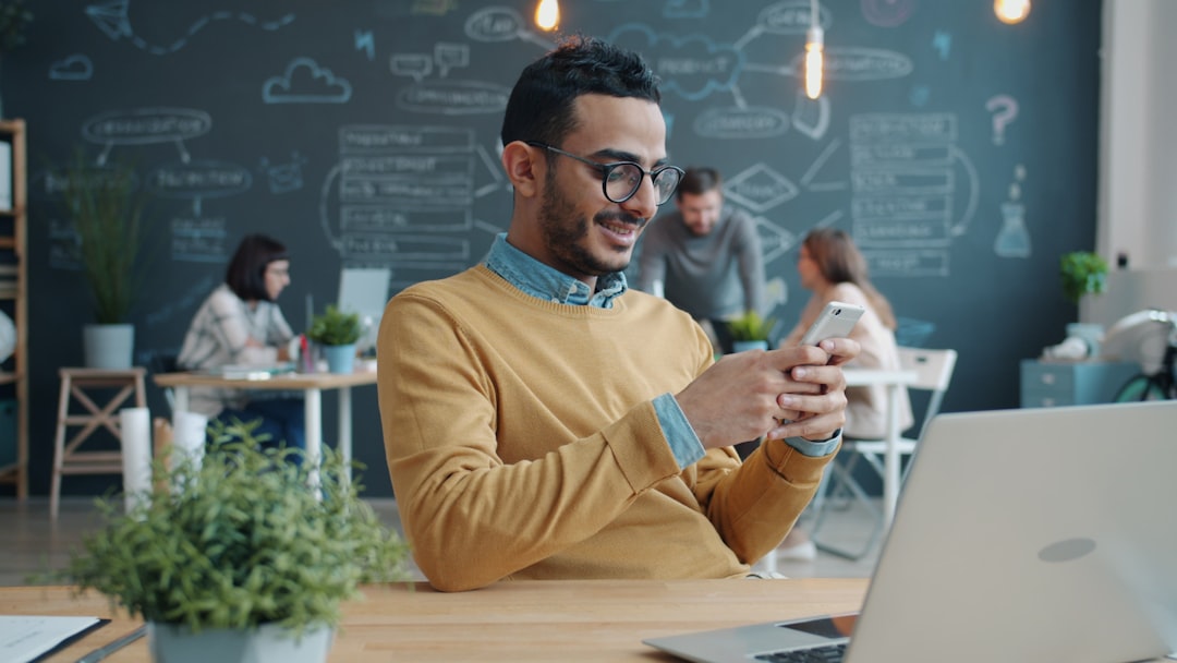 Man smiling while looking at his phone in office