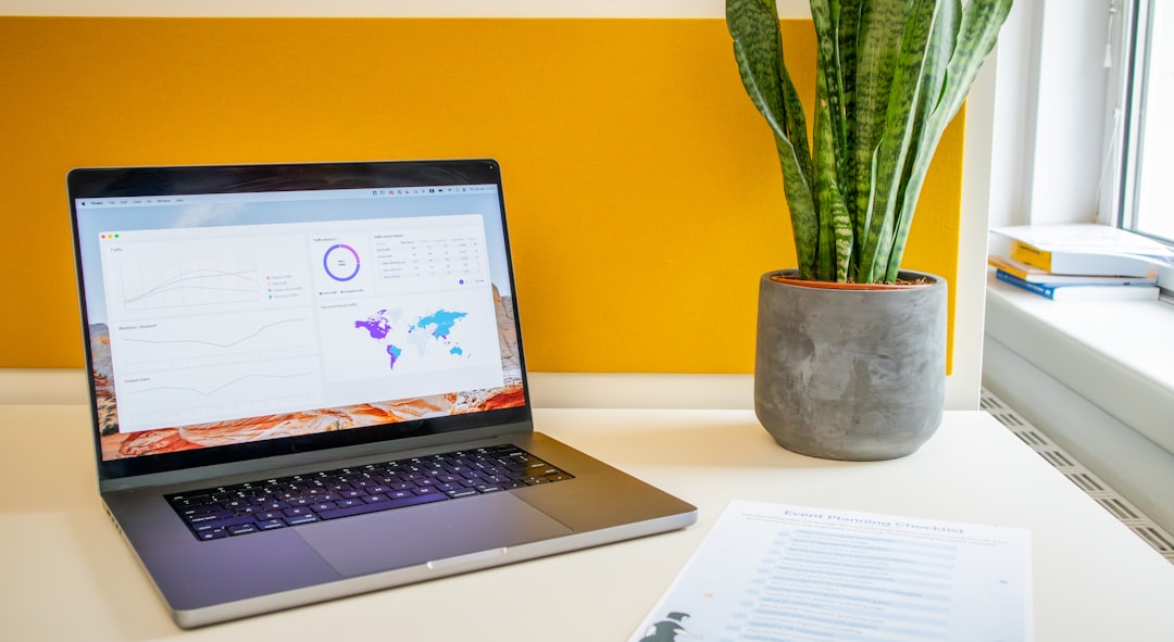 a laptop computer sitting on top of a desk next to a plant