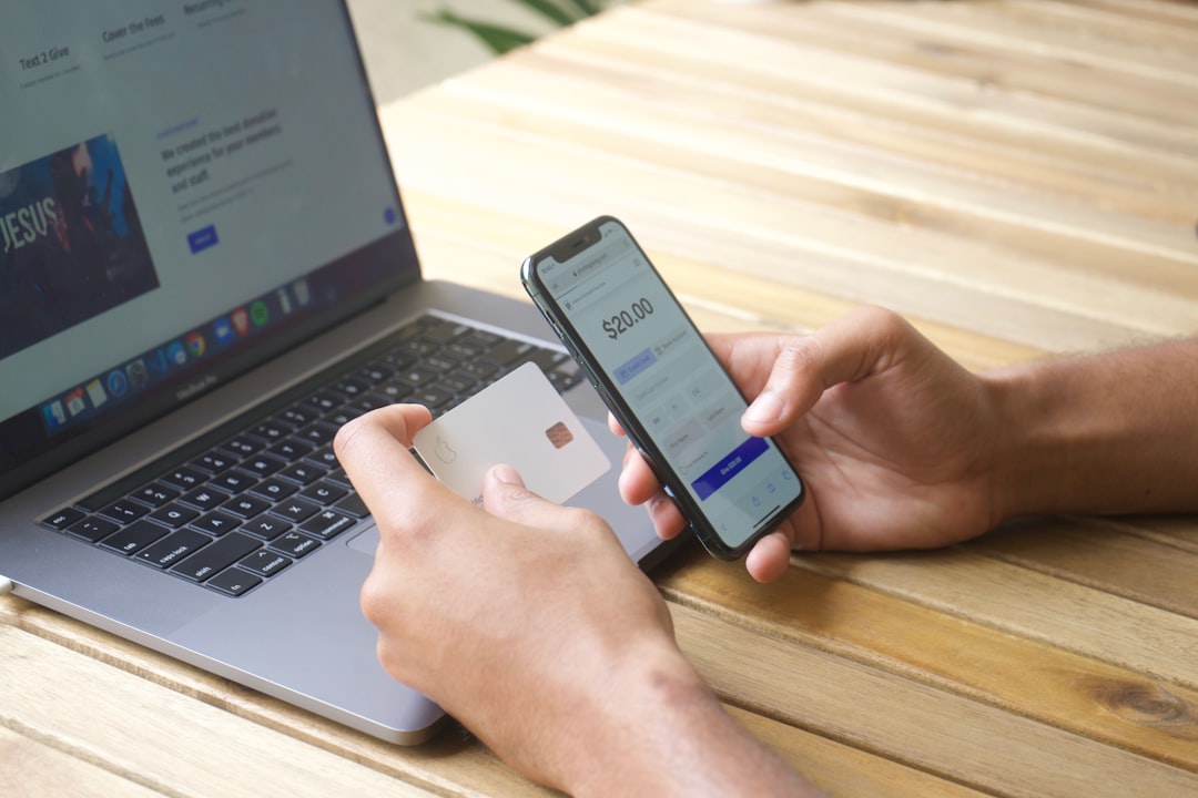 Person using smartphone and credit card with laptop