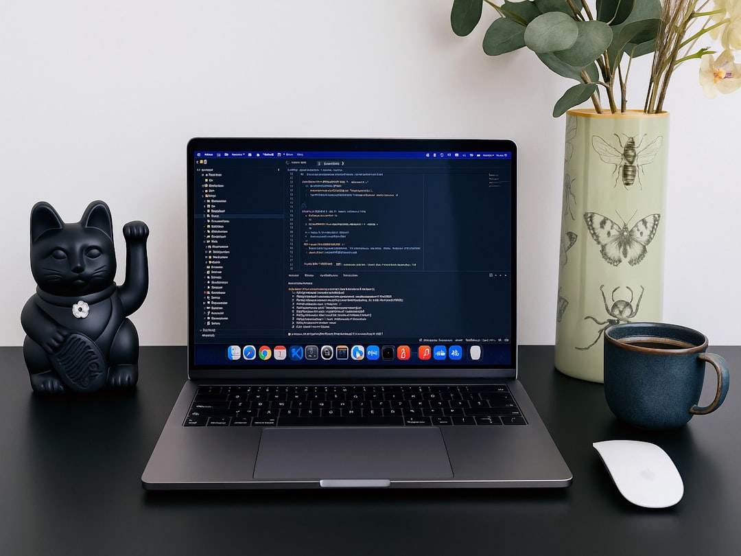 Laptop displaying code next to a lucky cat statue.