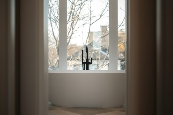 Modern bathtub with a black faucet by the window