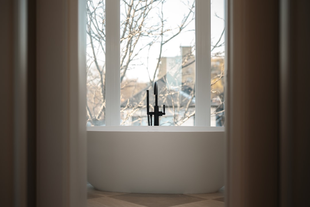 Modern bathtub with a black faucet by the window