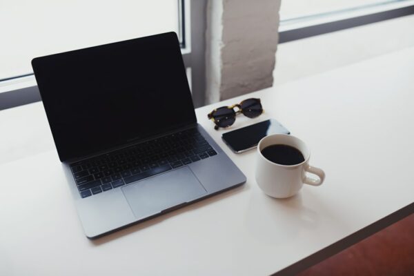 macbook pro beside white ceramic mug on white table