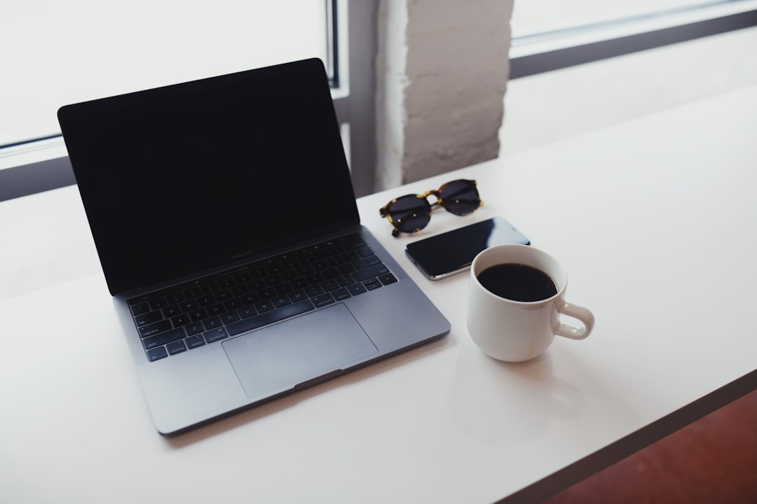 macbook pro beside white ceramic mug on white table
