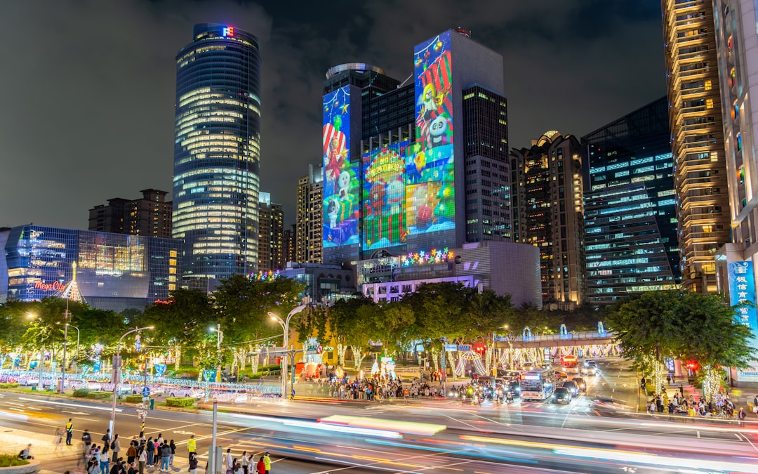 Cityscape at night with illuminated buildings and traffic trails.