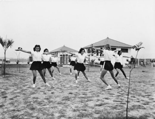 Women in athletic wear exercising outdoors near buildings.