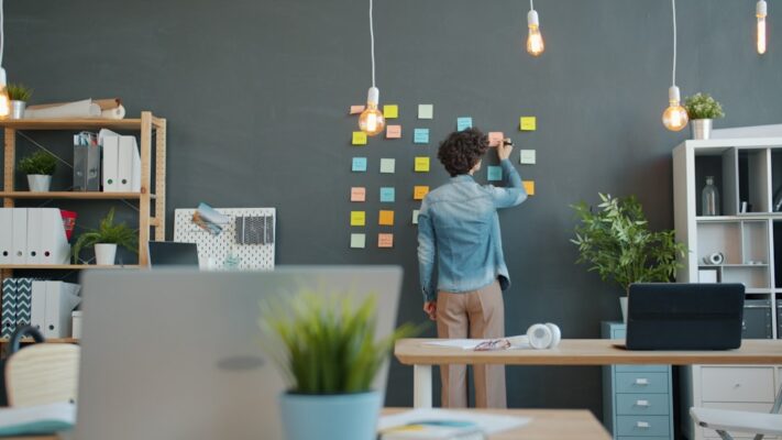 Person arranging sticky notes on a dark wall.